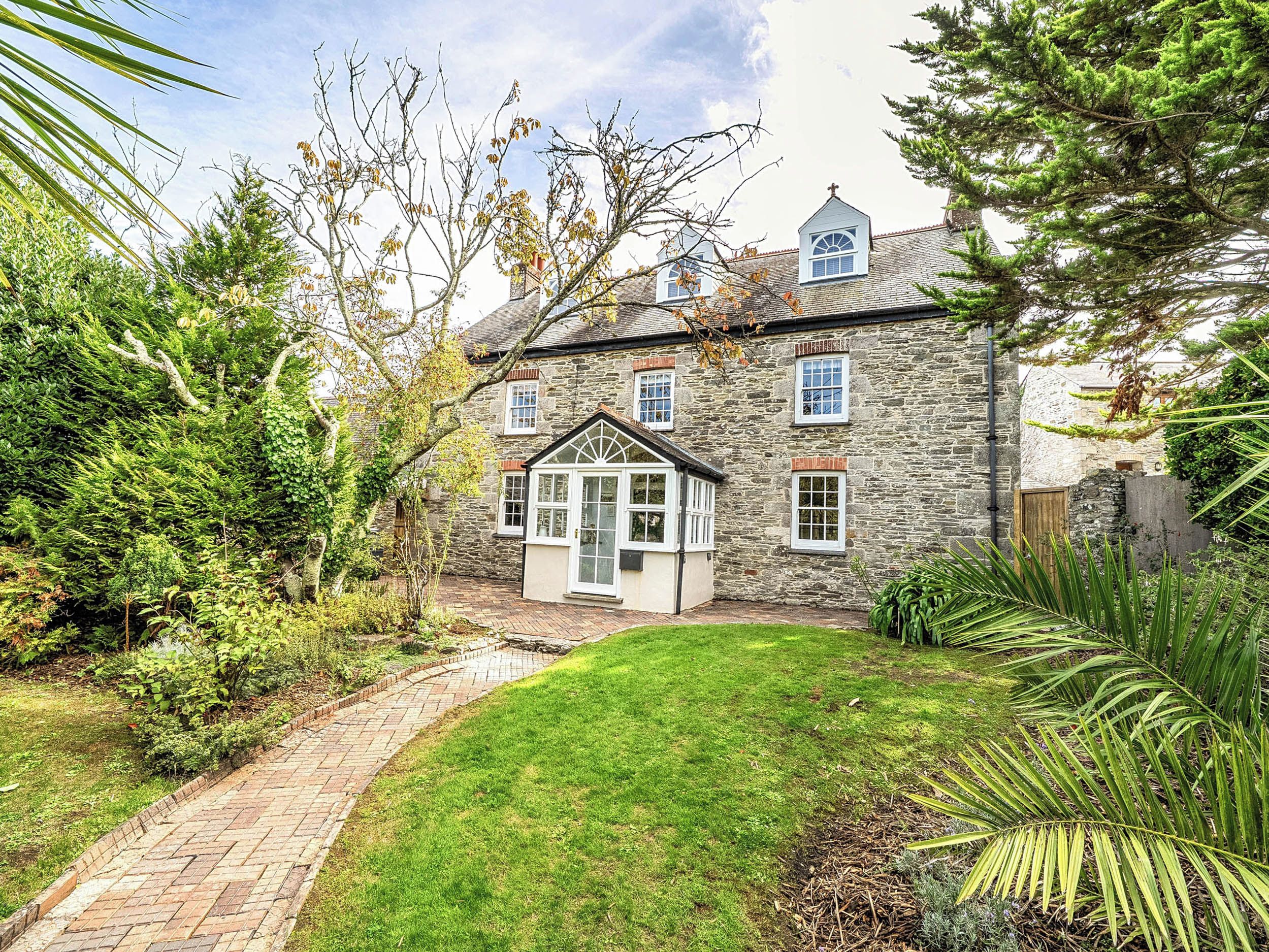 A stone house with a brick pathway leading to a small front garden.