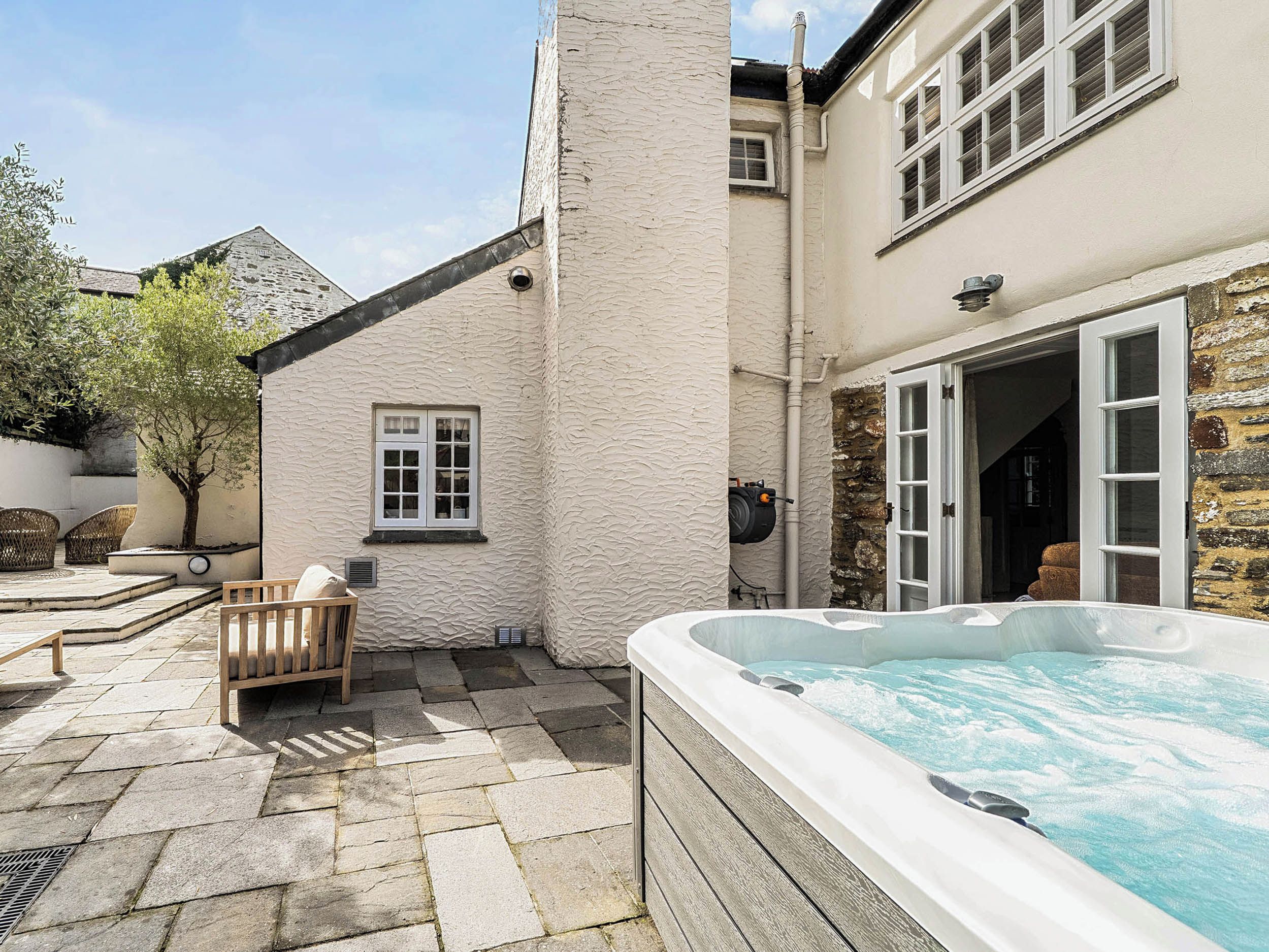 A spa area with a hot tub, stone flooring, and a wooden bench.