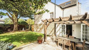 Un patio con una pérgola de madera, una mesa y sillas.