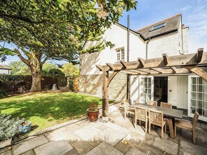 A patio with a wooden pergola, a table, and chairs. - Vosporth Villa (Newquay)