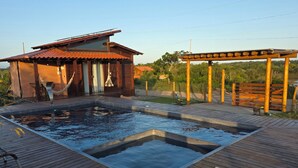 A wooden deck with a hot tub, a hammock, and a wooden pergola.