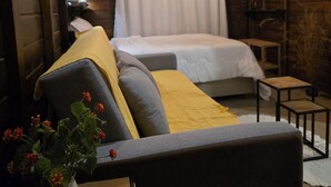 A cozy cabin room with a bed, a sofa, a small table, and a TV mounted on the wall.