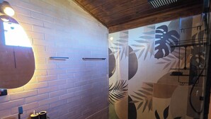 A bathroom with a wooden ceiling, a round mirror, a sink, and a toilet.