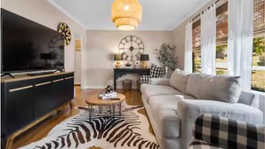 Un salon moderne avec un canapé, une table basse, un téléviseur et une grande horloge murale.