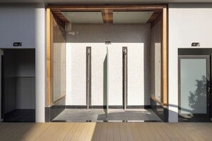A modern elevator with a minimalist design, featuring a glass enclosure and a wooden ceiling. - Stylish Studio with Balcony & Pool View in Arjan – Close to Miracle Garden (Dubai)