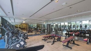 A modern gym with various exercise equipment, large windows, and a spacious layout. - Stylish Studio with Balcony & Pool View in Arjan – Close to Miracle Garden (Dubai)