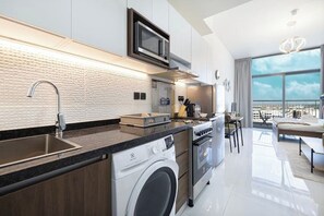 Une cuisine moderne équipée d’un lave-linge intégré, d’un four à micro-ondes et d’une grande fenêtre donnant sur la ville.