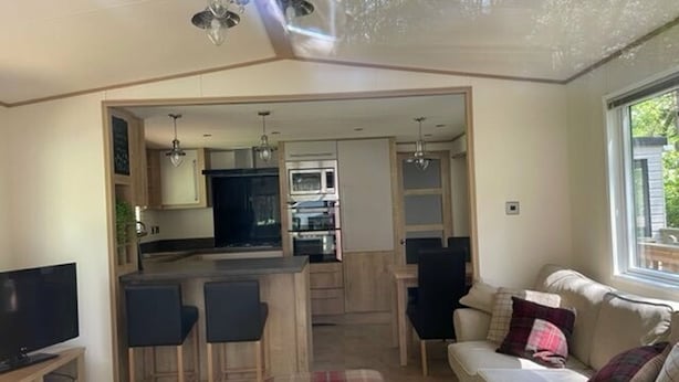 A compact living space with a kitchenette, a dining area, and a seating area with a sofa and chairs. - Living The Dream (Holt)