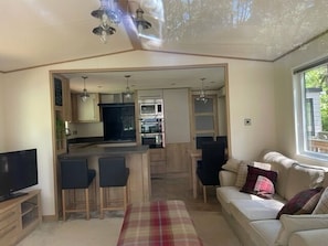 Un espacio habitable compacto con kitchenette, comedor y zona de estar con sofá y sillas.