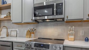 A modern kitchen with stainless steel appliances, including a microwave, oven, and dishwasher. - Park Hotel 1BR Suite 310 (Chattanooga)