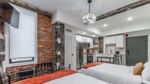Ein Zimmer mit zwei Betten, einer Ziegelwand, einer Küche und einer Tür.