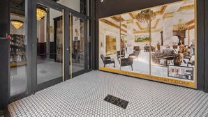 Eine moderne Hotellobby mit Glastür, Fliesenboden und einem großen Fenster, das den Innenbereich zeigt.