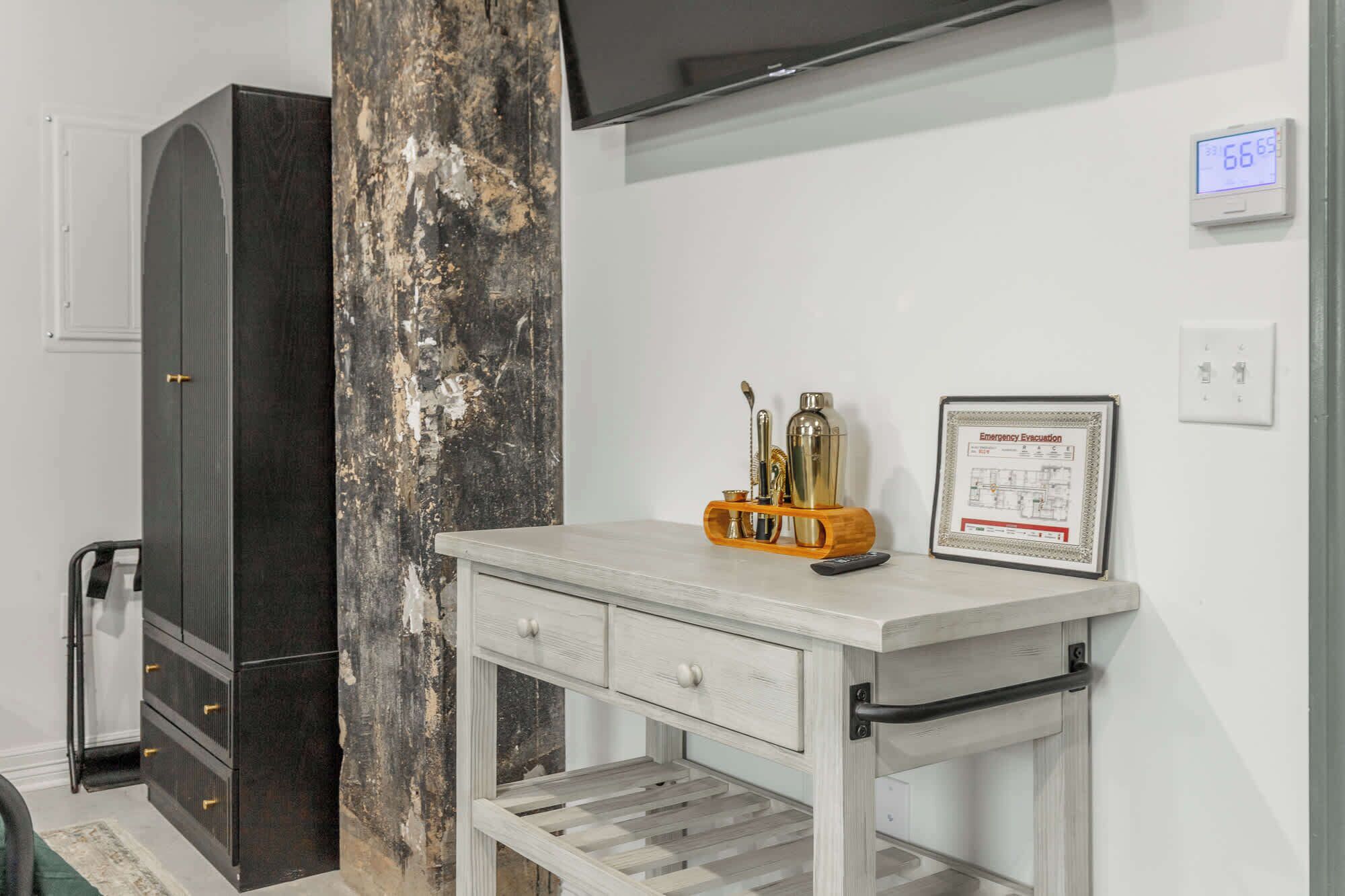 A room with a white desk, a framed emergency evacuation plan, a wall clock, and a large pillar.