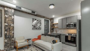 Een knus verblijf met een kitchenette, een bank, een bijzettafeltje en een decoratief wandobject.
