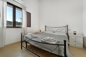A neatly arranged bedroom with a bed, bedside tables, and a window with curtains. - Villa Nuragica - Deluxe Apartment (Nuraxi Figus)