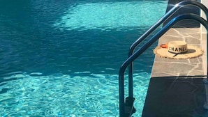 A clear indoor pool with a blue and white color scheme, a metal ladder, and a Chanel hat on the edge. - Villa Nuragica - Deluxe Apartment (Nuraxi Figus)