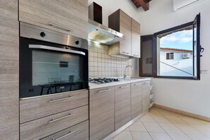 Cocina moderna con horno empotrado, estufa a gas y ventana con vistas al tejado.