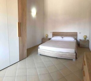 Une chambre à coucher comprenant un lit, une tête de lit en bois, deux tables de chevet avec des lampes et une armoire.