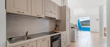 Una cucina con mobili in legno chiaro, un lavello in acciaio inossidabile e un forno integrato.