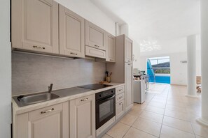 Una cocina con armarios de madera clara, un lavamanos de acero inoxidable y un horno empotrado.