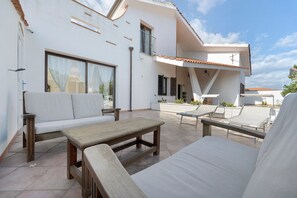 A modern outdoor patio with a sofa, a wooden table, and a lounge chair. - Villa Nuragica – Apartment with Private Pool (Nuraxi Figus)