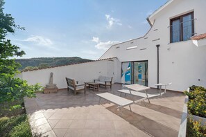 Une terrasse avec mobilier d’extérieur, un élément décoratif en pierre et une vue sur la campagne.