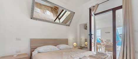 Une chambre d’hôtel avec un lit, une table de chevet, un miroir et une vue sur l’extérieur.