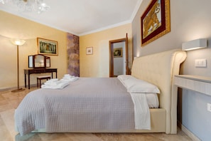 A hotel room with a bed, a desk, a chair, a lamp, and artwork on the walls. - Villa Nuragica - Apartment with Garden (Nuraxi Figus)