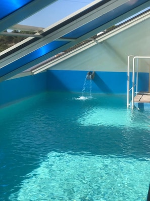 A swimming pool with clear water, a diving board, and a skylight. - Villa Nuragica – Apartment with Outdoor Kitchen and Terrace with View (Nuraxi Figus)