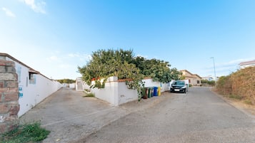 A residential street with houses, a car parked on the side, and a clear sky.
