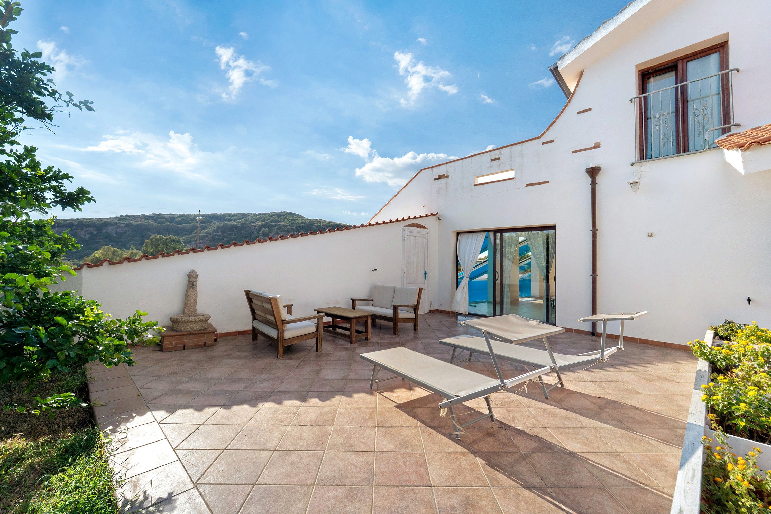 Un patio con mobiliario exterior, una estructura de piedra y vistas al paisaje.