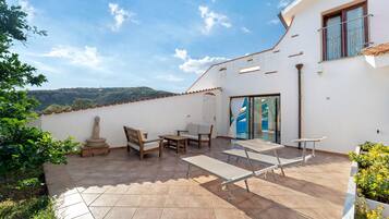 Un patio con mobiliario exterior, una estructura de piedra y vistas al paisaje.