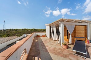 Une terrasse sur le toit agrémentée d’une pergola, de plantes en pot, d’une chaise longue et offrant une vue sur le paysage environnant.