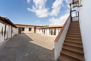 A courtyard with stone flooring, white walls, and a staircase leading to an upper level. - Villa Nuragica - Apartment (Nuraxi Figus)