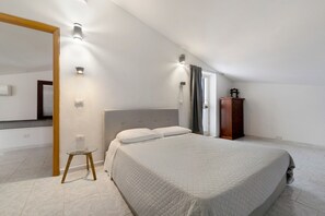 Une chambre à coucher comprenant un lit, une commode en bois, un miroir et des luminaires fixés au mur.