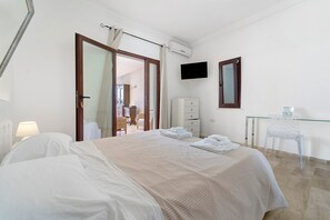 Una habitación de hotel con cama, escritorio, silla, televisión y armario.