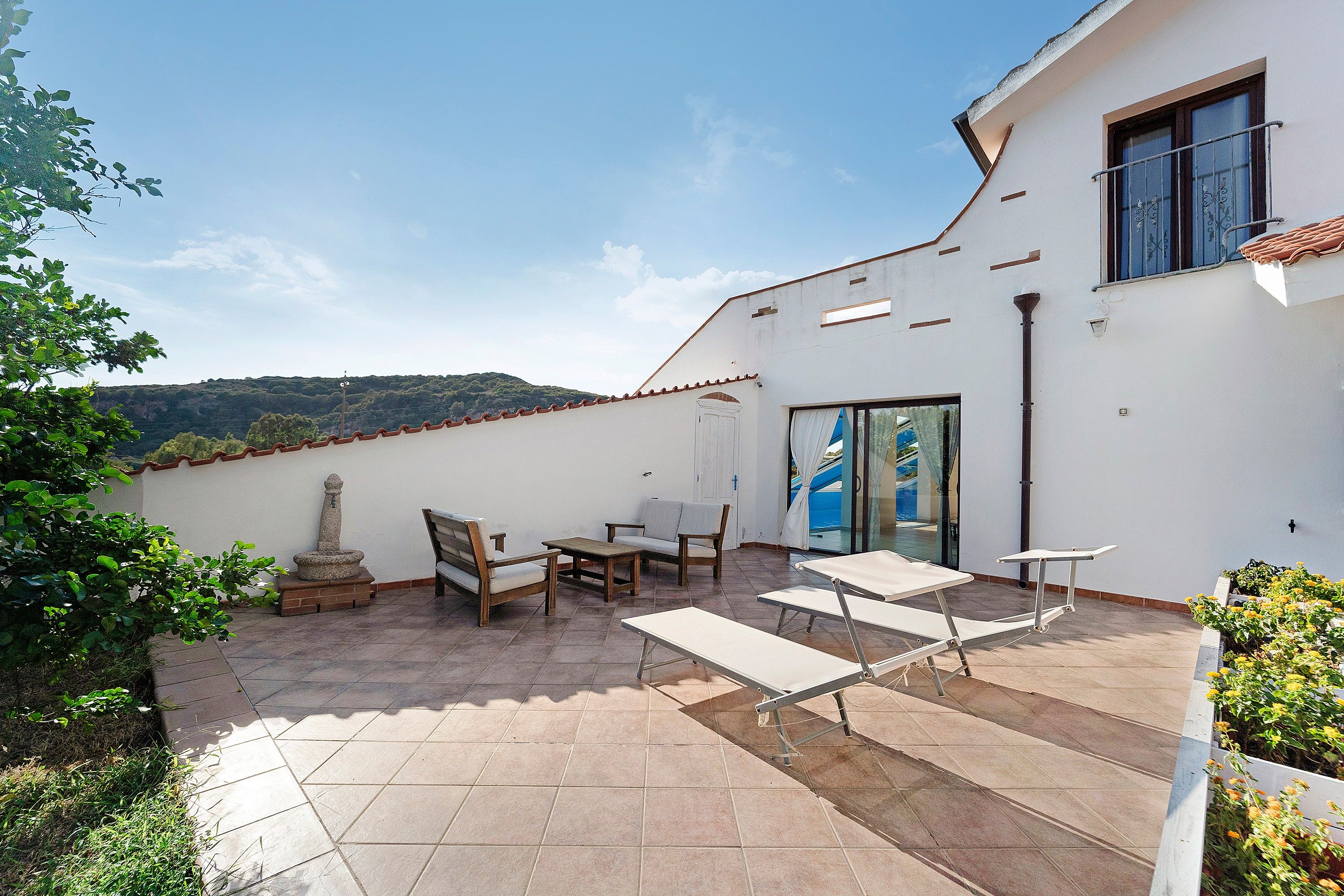 Eine Terrasse mit Gartenmöbeln, einer Steinpfeiler und Blick auf die Landschaft.