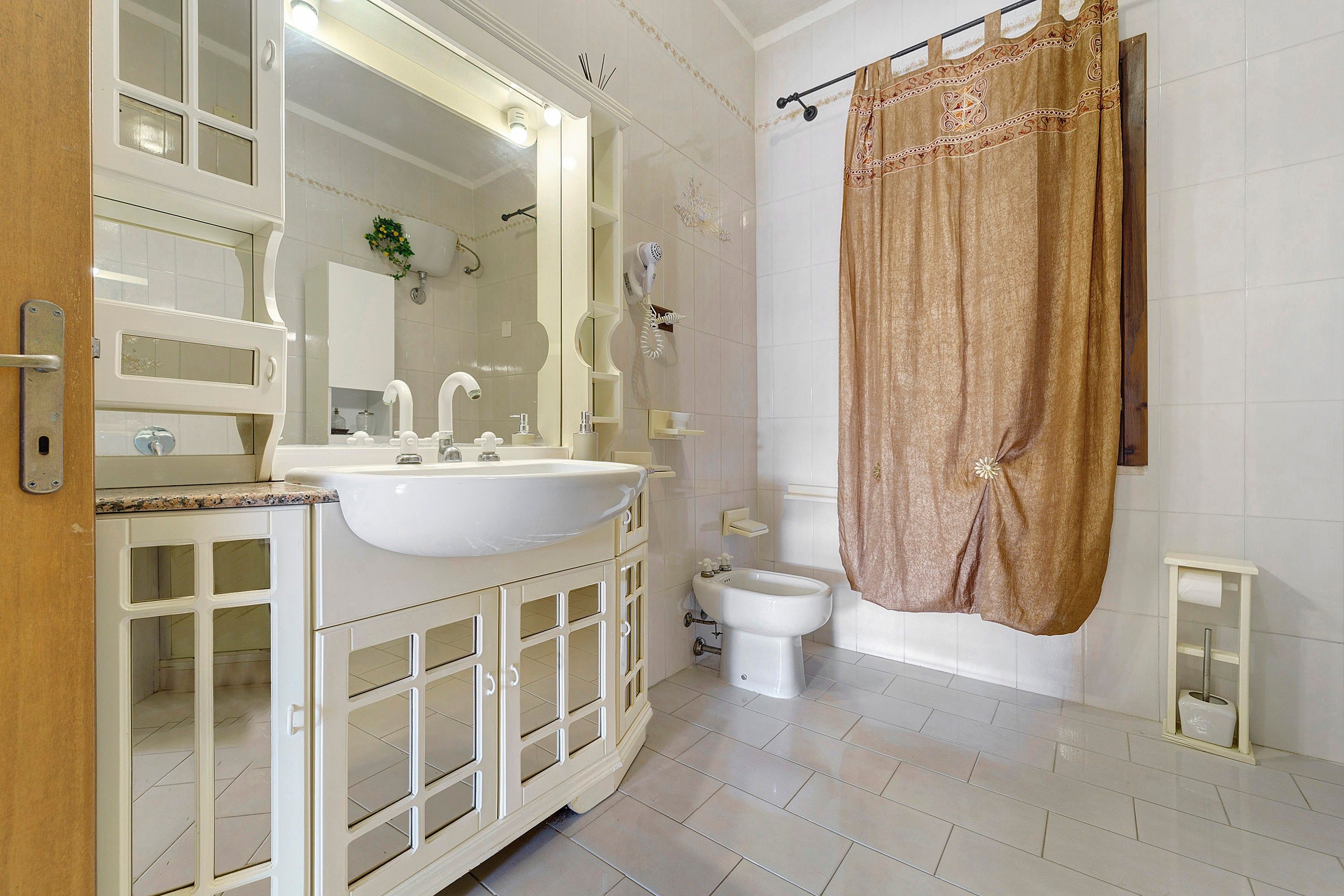 Un baño con lavamanos blanco, espejo y retrete.