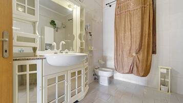 Un baño con lavamanos blanco, espejo y retrete.