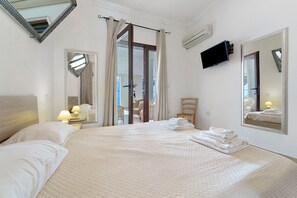 Une chambre d’hôtel avec un lit, une chaise, une télévision et un grand miroir.