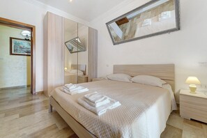 Een hotelkamer met een bed, nachtkastjes, een spiegel en een deur.