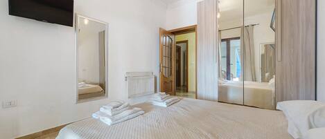 Une chambre à coucher comprenant un lit, un téléviseur à écran plat, un miroir et une armoire.
