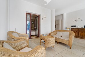 Una habitación con muebles de mimbre, una mesita y una zona de cocina con microondas.
