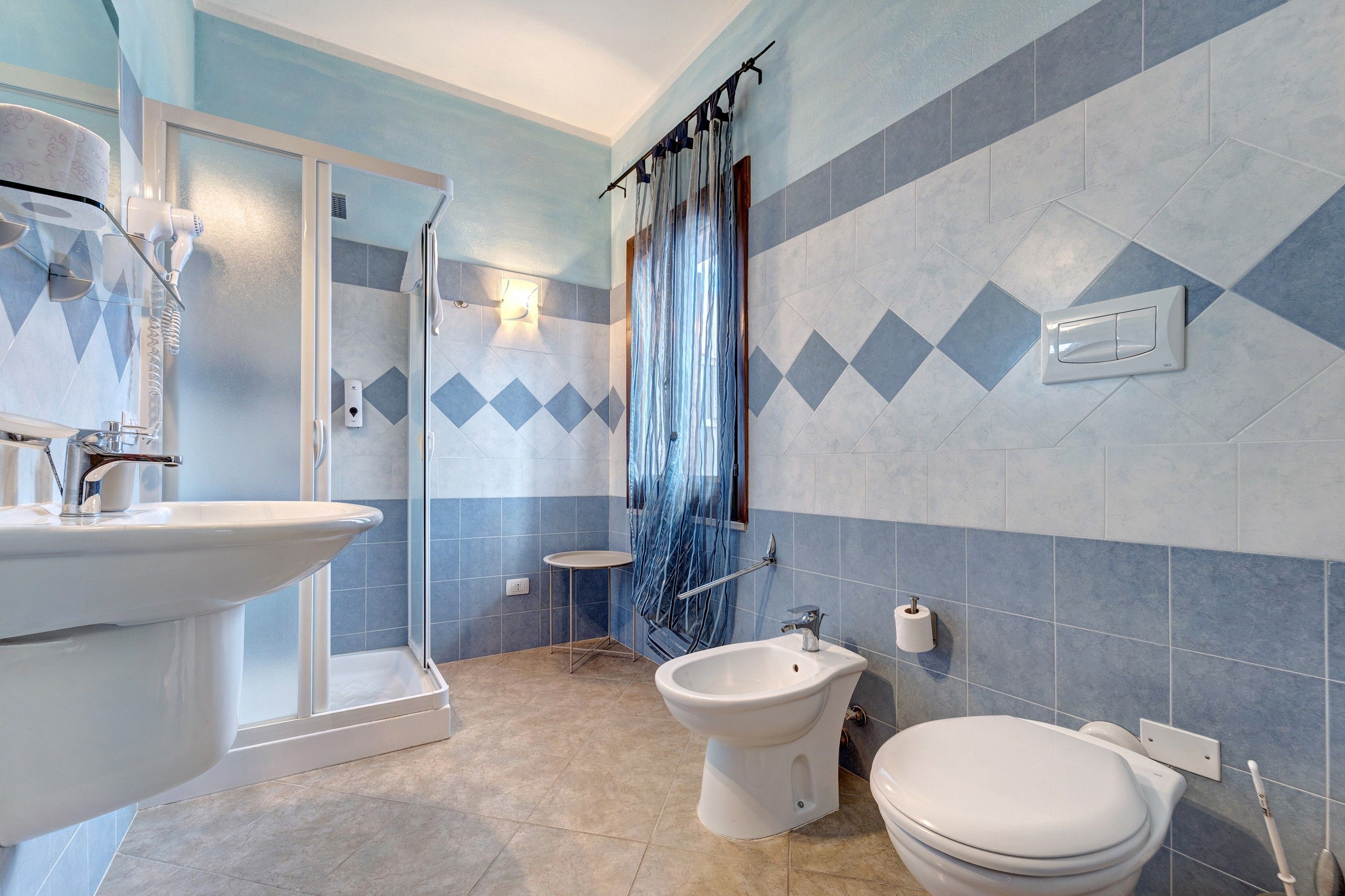 Een badkamer met een douche, toilet, wastafel en een bidet.