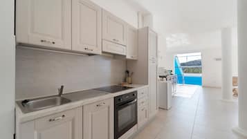 Een moderne keuken met witte kasten, een RVS spoelbak en een ingebouwde oven.