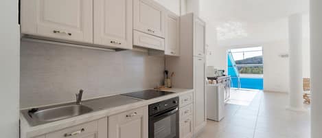 A modern kitchen with white cabinetry, a stainless steel sink, and a built-in oven.