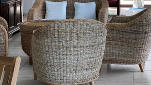 A room with wicker furniture, a cabinet, and a view of the outdoors. - Villa Nuragica – Room with Private Bathroom (Nuraxi Figus)