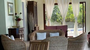 A dining area with wicker furniture, a glass table, and a view of the outdoors. - Villa Nuragica – Room with Private Bathroom (Nuraxi Figus)
