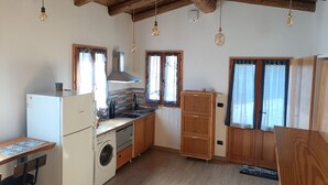 A compact kitchen with wooden cabinets, a built-in washing machine, a sink, and hanging light bulbs. - The house on the rainbow (Piemonte)