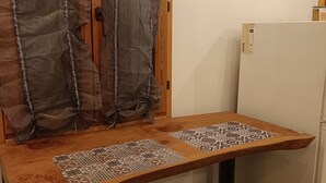 A small kitchenette with a wooden countertop, two patterned placemats, a refrigerator, and a window with sheer curtains. - The house on the rainbow (Piemonte)